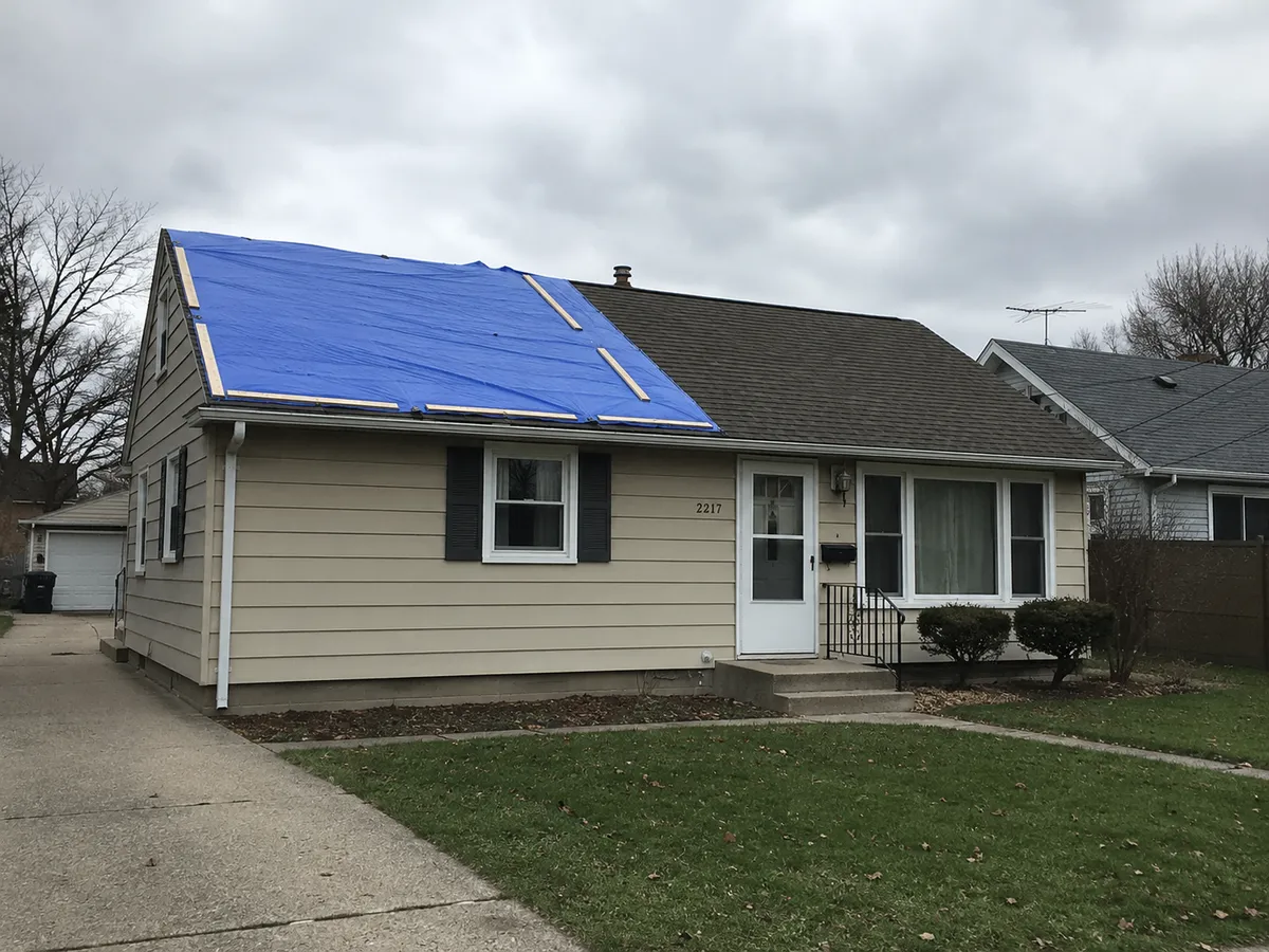 A tarp covering a storm-damaged roof section on a Milwaukee home