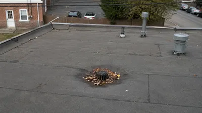 A flat roof drain clogged with leaves, a common maintenance issue on Milwaukee flat roofs
