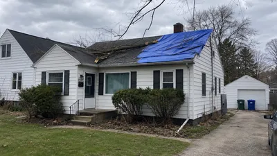A Milwaukee home with a tarp covering storm damage from a fallen branch